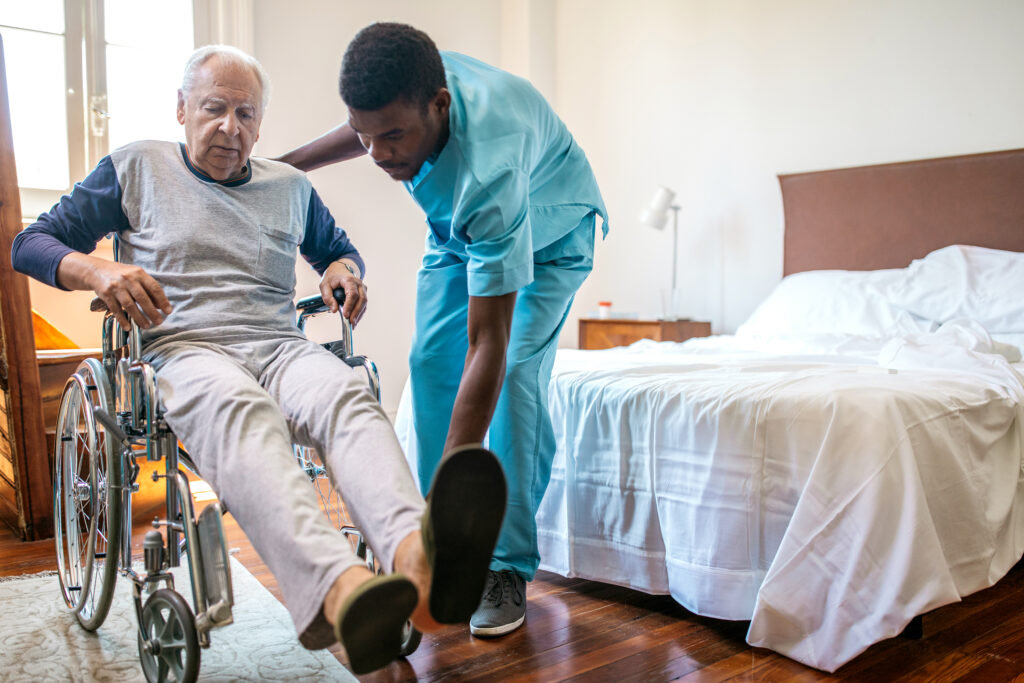 man nurse helping senior in wheelchair in nursing home man nurse helping senior in wheelchair in nursing home